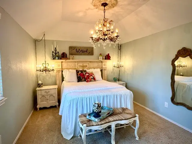 Bedroom beneath a grand vintage chandelier, made up with crisp white linens