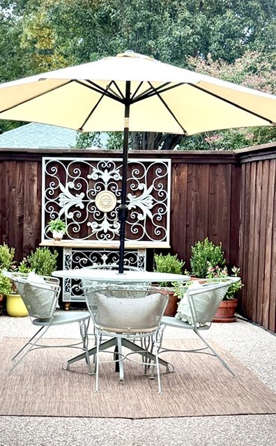 The back patio table for four, under a cream umbrella