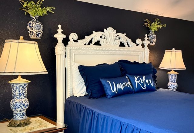 The navy bedroom, with its ornate white bed frame and blue-and-white lamps