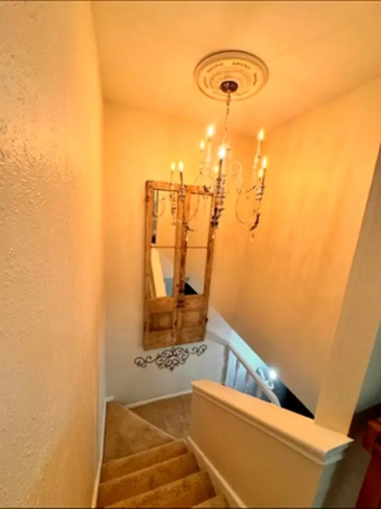 The stairwell chandelier at the top of the landing, above an antique mirrored door and iron scrollwork