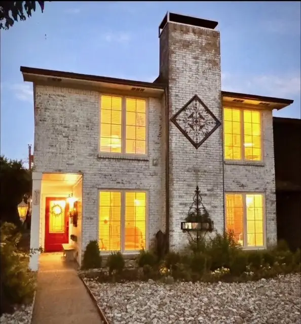 The Rustic Chandelier at dusk, warm light glowing from every window and the red front door
